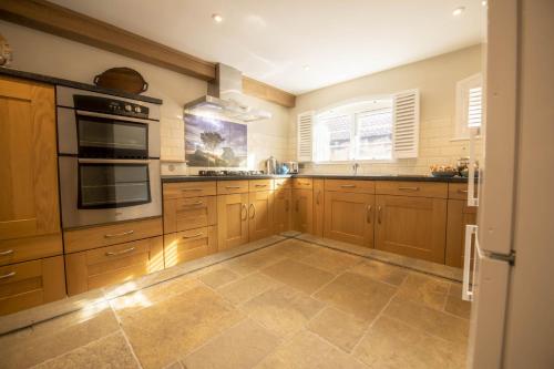 a large kitchen with wooden cabinets and appliances at 1 School Lane in Malton