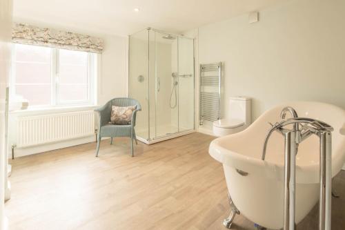 W łazience znajduje się wanna, krzesło i prysznic. w obiekcie 1 School Lane w mieście Malton