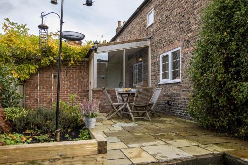 a patio with a table and chairs in a brick house at 1 School Lane in Malton