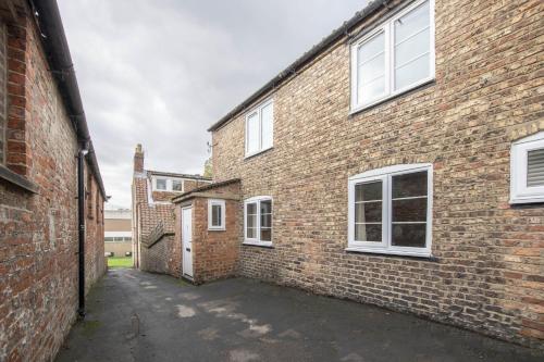 an alleyway between two brick buildings with white windows at 1 School Lane in Malton