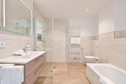 een badkamer met een bad, een wastafel en een toilet bij Landhaus am See Appartement LH 02 in Schwangau