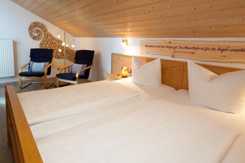 a bedroom with a large bed and two chairs at Salenberghof Ferienwohnung Traumblick in Rieden am Forggensee