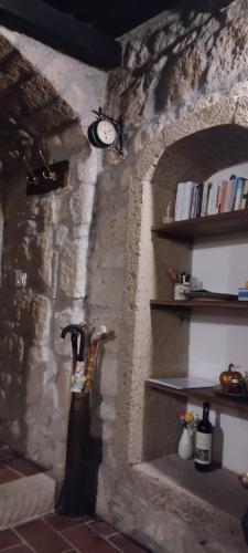 a room with a stone wall with a clock on the wall at LA CHASCONA DI FARNESE casa di tufo nel borgo in Farnese