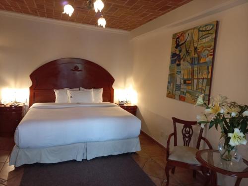 Un dormitorio con una gran cama blanca y una mesa en Marhialja Hotel Boutique, en Oaxaca City
