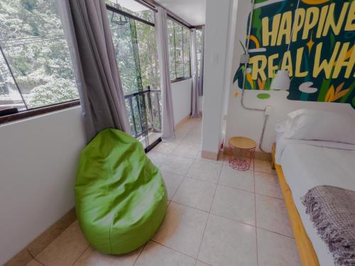 a living room with a couch and a green ottoman at Supertramp Hostel Machupicchu in Machu Picchu