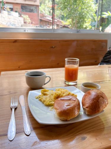 a breakfast plate with eggs and biscuits and a glass of orange juice at Supertramp Hostel Machupicchu in Machu Picchu