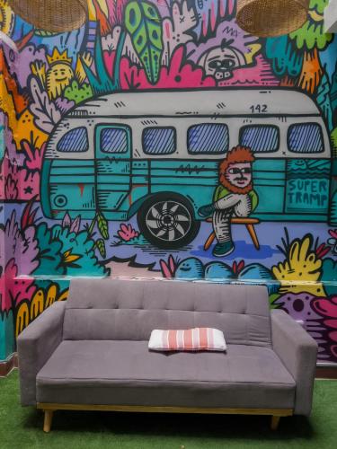 a couch in front of a mural with a bus at Supertramp Hostel Machupicchu in Machu Picchu