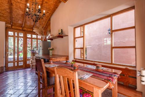 a kitchen with a wooden table and some windows at Unuwasi Hotel & Villa in Calca