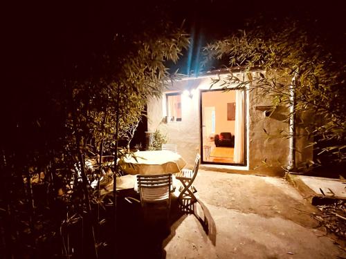 una mesa y una silla frente a una casa por la noche en Casa les bambous, en Nimes