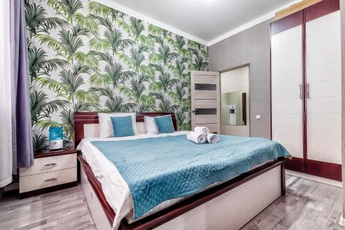 ein Schlafzimmer mit einem Bett mit einer tropischen Tapete in der Unterkunft Комфортная квартира в центре города in Astana