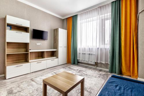 ein Wohnzimmer mit einem TV und einem Tisch in der Unterkunft Комфортная квартира в центре города in Astana