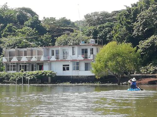 a person on a raft in the water in front of a house at La Cabaña del Lago in Catemaco
