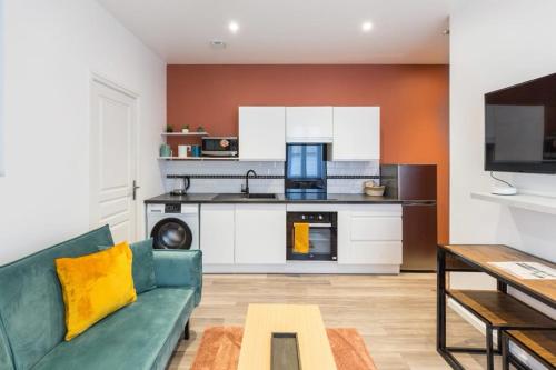 uma sala de estar com um sofá verde e uma cozinha em Terra logement cosy et charmant em Reims