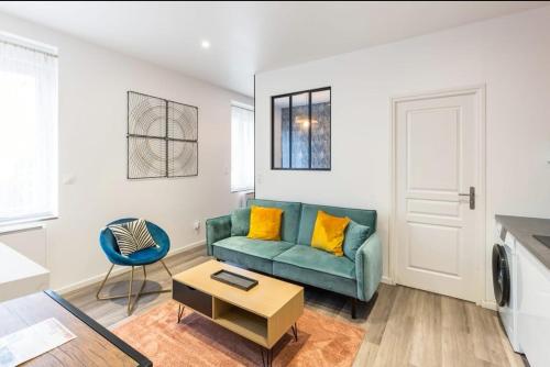 Terra logement cosy et charmant في رانس: غرفة معيشة مع أريكة خضراء وطاولة