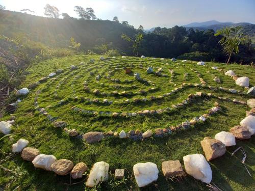 a grassy hill with a clock in the middle at Uaná Etê EVEN GLAMPING Experiências de Charme in Engenheiro Paulo de Frontin