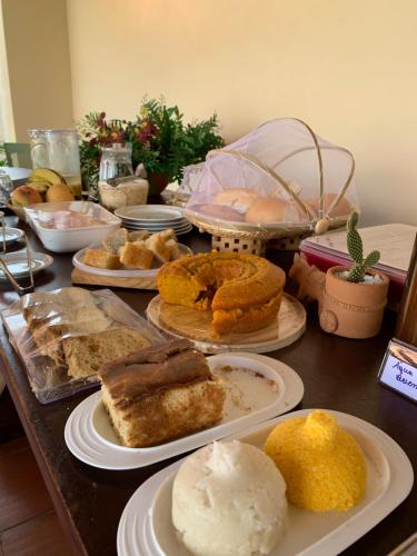 a table topped with plates of pastries and pies at POUSADA DOS LAGOS in Paulino Neves