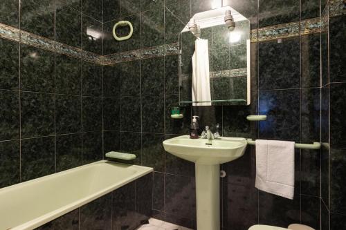 y baño de azulejos negros con lavabo y bañera. en El Bajondillo Beach a 30 metros de la playa en Torremolinos