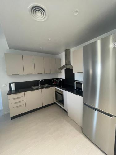 una cucina con armadi bianchi e frigorifero in acciaio inossidabile di Apartamento Coman Av Rey Juan Carlos I a Torrent