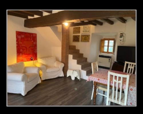 uma sala de estar com mobiliário branco e uma escadaria em C'era una volta a Piozzano Casa Rustica em Piozzano
