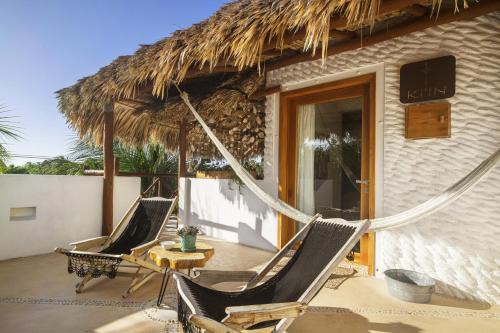 two chairs and a table on a house with a thatch roof at El Corazón Boutique Hotel - Adults Only with Beach Club pass included in Holbox Island