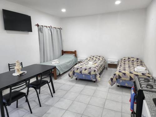 a room with two beds and a table and chairs at Monoambiente en el centro de la Ciudad. in Mercedes