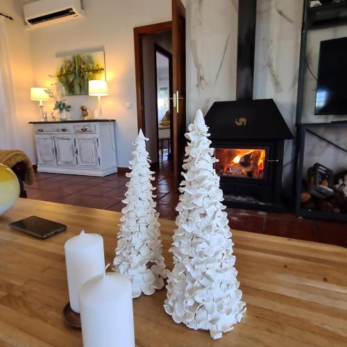 two white christmas trees on a table with a fireplace at Villa Prana in Avila