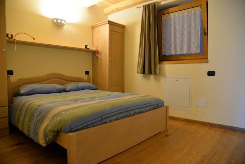 - une chambre avec un lit doté d'une tête de lit en bois et d'une fenêtre dans l'établissement Agriturismo Valsaviore, à Cevo
