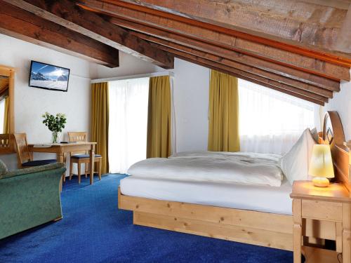a bedroom with a bed and a desk and a chair at Hotel Plateau Rosa in Zermatt