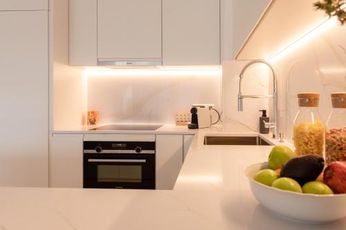 a white kitchen with a bowl of fruit on a counter at Hamilius Apartments City Center Luxembourg by Rentaroo in Luxembourg