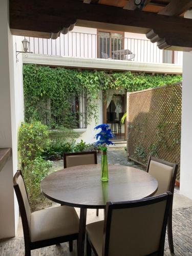 a table with chairs and a vase with blue flowers on it at El Calvario Lofts in Antigua Guatemala