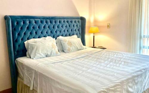 1 cama grande con cabecero azul y almohadas blancas en Luxurious 3 BR Rustic Apartment Overlooking Huge Garden - For Families and Couples en El Cairo