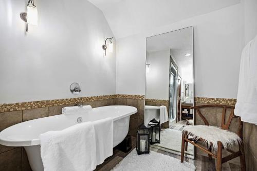 un bagno bianco con vasca e specchio di Luxury Penthouse At Solar A Resort And Spa a Canmore