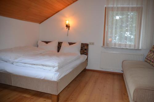 a bedroom with a white bed and a couch at Ferienhaus Ferch in Turracher Hohe