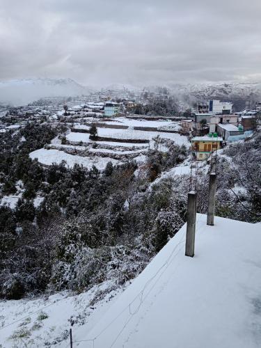 a snow covered hill with a town in the distance at Veda Inn in Chakrāta