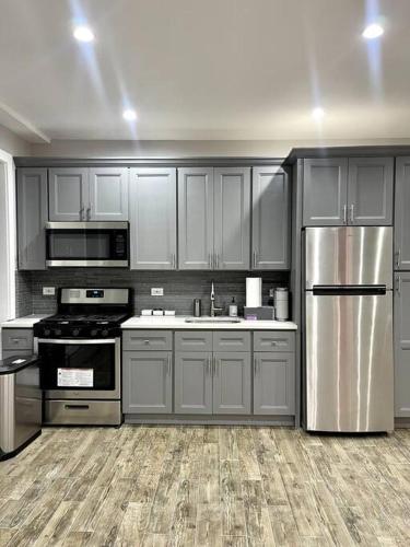 een keuken met grijze kasten en roestvrijstalen apparatuur bij Cozy cottage in Bronx with good bedrooms in West Farms