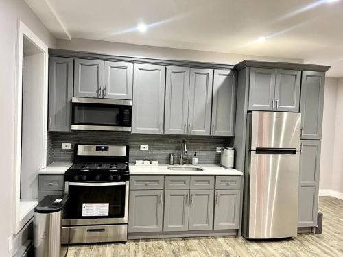 een keuken met roestvrijstalen apparatuur en grijze kasten bij Cozy cottage in Bronx with good bedrooms in West Farms