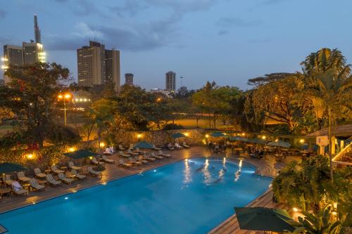 a swimming pool with lounge chairs and a city skyline at Nairobi Serena Hotel in Nairobi