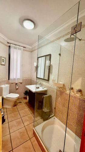 a bathroom with a tub and a toilet and a sink at Amplio piso en centro histórico. in Toledo