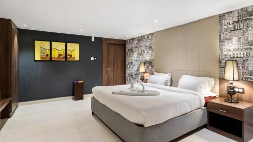 a bedroom with a large white bed and a wall at Niranjana Hotel Bodhgaya in Bodh Gaya