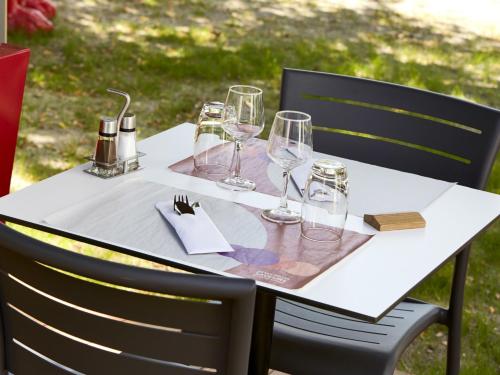 a white table with wine glasses on it at Campanile Bordeaux Ouest - Mérignac Aéroport in Mérignac