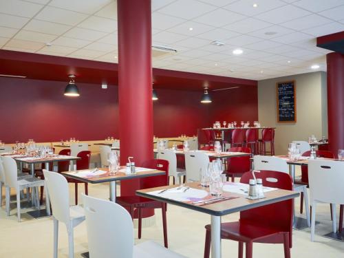 a restaurant with tables and white chairs and red walls at Campanile Bordeaux Ouest - Mérignac Aéroport in Mérignac