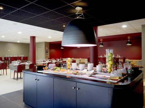 a kitchen with a counter top and a table with plates of food at Campanile Bordeaux Ouest - Mérignac Aéroport in Mérignac