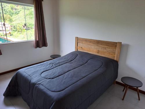 a bedroom with a bed with a blue blanket and a window at A Casa do Júnior em Visconde de Mauá in Visconde De Maua