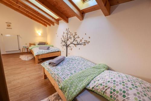 a bedroom with two beds and a tree on the wall at Ferienwohnung Feichtlgütl in Marktschellenberg