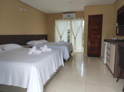 a bedroom with two beds with white sheets at Pousada Bellissima Italia in Luis Correia