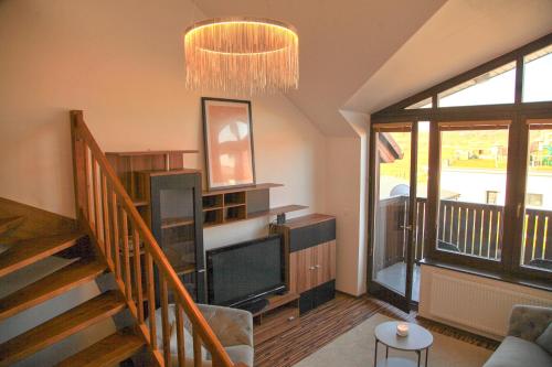 a living room with a television and a staircase at Apartment Vila Aston in Veľká Lomnica