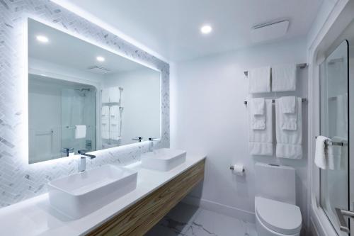 a white bathroom with two sinks and a mirror at Strata Hotel in Kingston