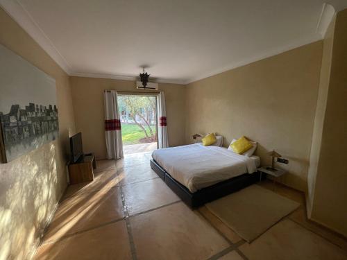 - une chambre avec un lit et une grande fenêtre dans l'établissement Le Mas de l’Ourika, à Marrakech