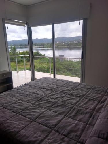 a bedroom with a bed and a view of a lake at lacasonavistalago in Villa Carlos Paz