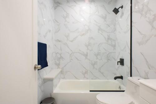 La salle de bains blanche est pourvue d'une douche et de toilettes. dans l'établissement 240-14 NEW Studio Prime Location W&D in unit, à New York